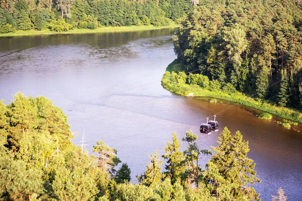 Two cable cars on the background of the river and green forest