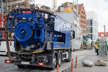Arkasında binalar olan taştan bir kaldırımda büyük mavi bir kamyon.