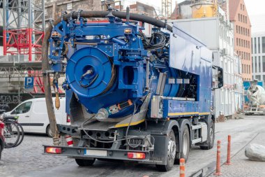 Arkasında binalar olan taştan bir kaldırımda büyük mavi bir kamyon.