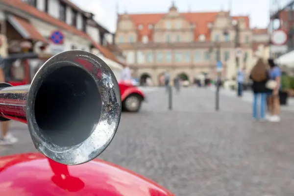 metal horn on red car fender on background of city streets