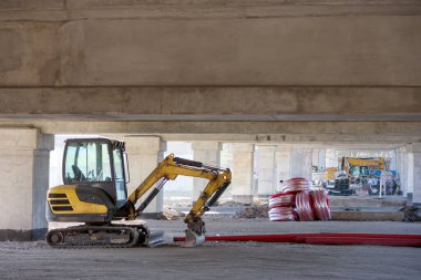 Tarım arazisi traktörü köprünün altında bir kova ile çalışıyor.