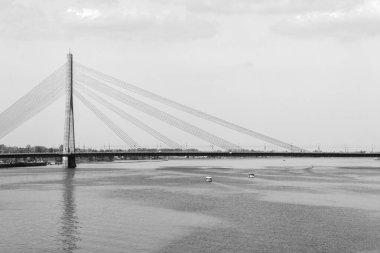 Sabahları bir nehir üzerindeki bir köprünün siyah beyaz görüntüsü