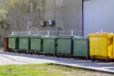 Gri bir binanın duvarındaki çöp konteynırları
