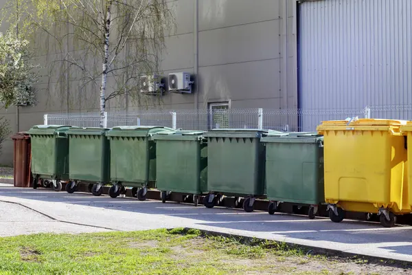 Gri bir binanın duvarındaki çöp konteynırları