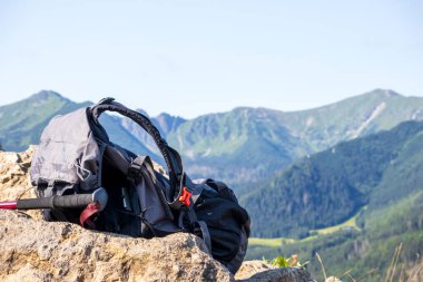 Mavi gökyüzü olan dağların arka planındaki çantalardan ve direklerden yürüyüş ekipmanları
