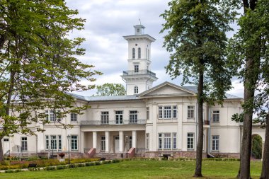 Önünde büyük parlak bir ev ve çiçek bahçesi olan bir park.