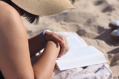 Kumsalda kitap okuyan bir kadın.