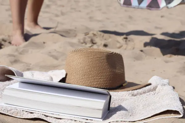 Kumsalda okunacak bir kitabı olan güneş şapkası.