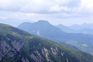 Gökyüzünün arka planında bir dağ vadisi olan dağlardaki doğal manzara.