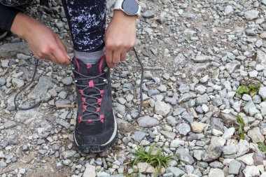 Bir adam çizmesini bağlar ve yol boyunca yürür.