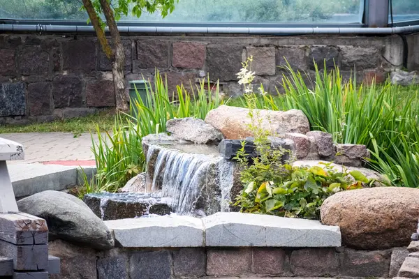 Bahçenin ortasında çiçeklerle dolu bir çeşme.