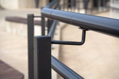 Bir metal korkuluk parçası. Tırabzan kare metal desteklere bağlı iki paralel boru sapından oluşuyor. Sapları ve destekleri siyaha boyanmış..