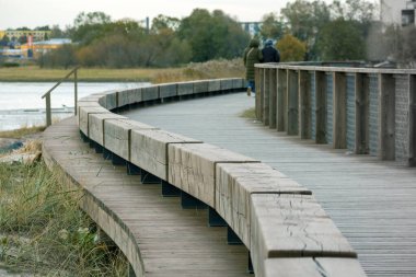 Kavisli ahşap bir köprü sahil boyunca insanların içinde olduğu bir köprü.