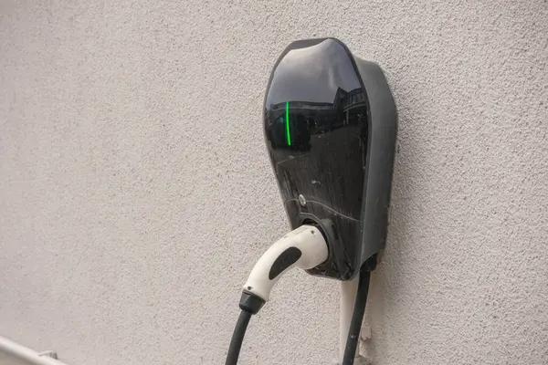 Duvarda siyah elektrikli araba fişi var.