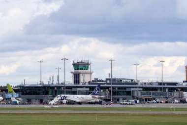 Kalkışa hazırlanan bir uçağı ve arka planda kontrol kulesi olan büyük bir uluslararası havaalanı kompleksi..