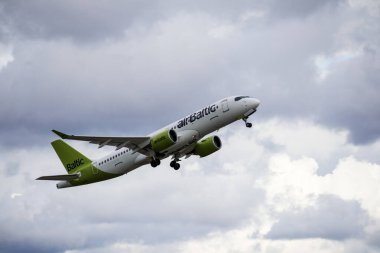 Arka planda beyaz bulutlar olan bir uçak mavi gökyüzünde havalanır..