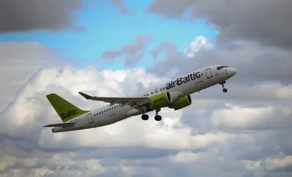 Airlines Airbus A220, arka planda beyaz bulutlarla mavi gökyüzünden kalkıyor.