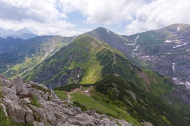  Karla kaplı tepeleri, dik yamaçları ve ender ağaçlar ve çalılarla kaplı yeşil vadileri olan bir dağ sırası..
