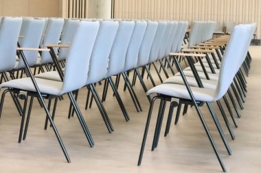 Konferans salonunun boş bir parçası ya da tahta kollu gri sandalyeli oditoryum..