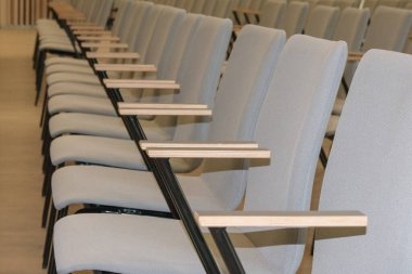 Konferans salonunun boş bir parçası ya da tahta kollu gri sandalyeli oditoryum..