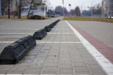 Siyah kaldırım blokları beyaz çizgili bir çizgi boyunca dizilmiş boş bir park yeri..