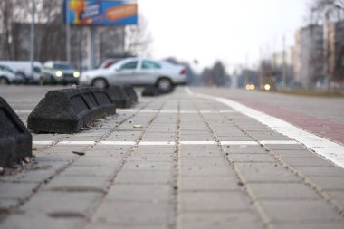 Siyah kaldırım blokları beyaz çizgili bir çizgi boyunca dizilmiş boş bir otoparkın köşesi..