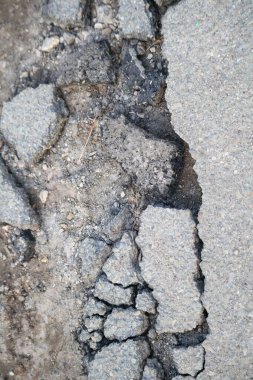 Büyük çatlaklar ve hasarlı asfalt bir yola yakın çekim.