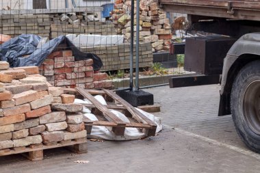 Tuğlaları ve paletlerin üzerine yığılmış bir kamyoneti olan bir inşaat alanı..