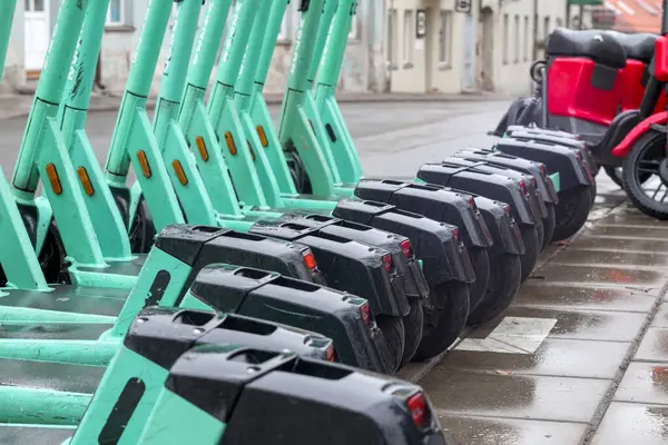 Sokakta değişik renklerde birkaç elektrikli scooter dizilmiş..