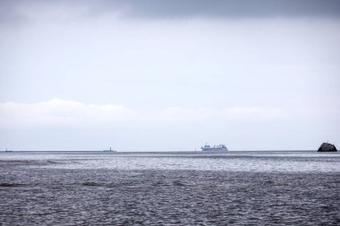 Sakin suyu olan bir körfez ve uzaktan görünen bir gemi..