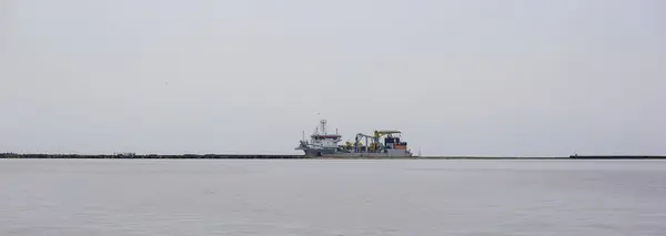 Sarı asansörlü büyük gri bir yük gemisi..