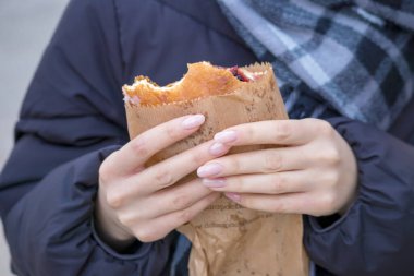 Bir insan elinde yiyecek dolu bir kese kağıdı tutarken görülüyor..