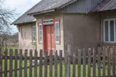 Önünde ahşap çitler olan eski bir kır evi..