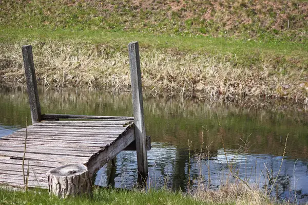 Küçük bir gölet ya da hendek boyunca uzanan küçük tahta bir köprü..