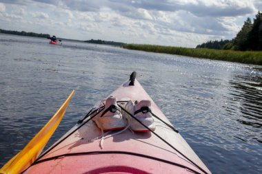 Nehirde yüzen bir kano ve arkasında bulutlu bir gökyüzü..