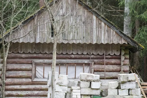 Önünde beton bloklar olan eski ahşap bir bina..