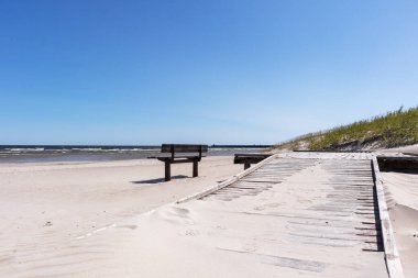 Sahilde bir bank ve denize uzanan beton bir patika..