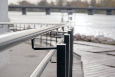 Arka planda nehir ve köprü olan metal parmaklıklar..