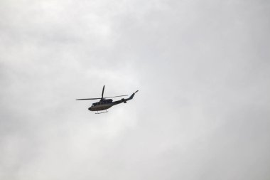 Şehirdeki bir otoparkta birkaç arabanın arasına park etmiş sarı bir scooter..