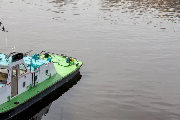 Çerçeveye kısmen dahil edilmiş, yeşil güverteli ve açık mavi çatılı küçük, beyaz bir gemi..