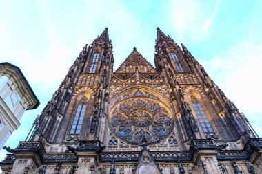 Görkemli Gotik bir katedralin ön cephesi, yüksek kuleleri, karmaşık taş oymaları ve merkezde büyük bir gül penceresi de dahil olmak üzere vitraylı pencereleri vurguluyor..