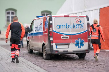 Kırmızı ve mavi çizgili beyaz bir ambulans ve sokakta 