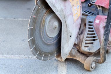 İnşaat aleti, büyük ihtimalle beton ya da asfalt kesici, büyük metal bir bıçak ve aşınma izleri var..