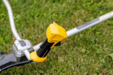  Yeşil bir çimenlikte dinlenen bir tel budayıcının sarı ve siyah sapına yakın plan, bahçe aletleri ve açık hava işleri.