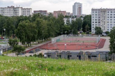  Riga 'nın şehir manzarasında ağaçlarla ve çeşitli yerleşim yerleriyle çevrili koşu pisti ve egzersiz alanı olan canlı bir spor parkı..