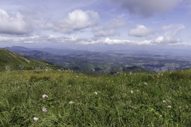 Geniş bir vadinin yüksek irtifasından panoramik bir manzara. Köyler, yeşil alanlar ve uzak dağlar..