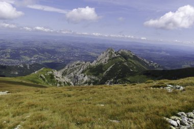 Yüksek bir dağ noktasından güzel bir panoramik manzara, vadideki geniş bir kasabaya tepeden bakan yeşil ve kayalık bir sırtı gösteriyor..