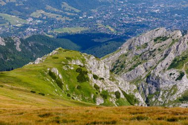 Kayalık ve yeşil bir dağ sırtına yakın, aşağıdaki geniş vadide görülebilen güzel bir kasaba aydınlık bir günde..
