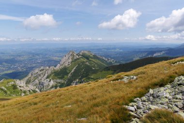 Kayalık bir yamaçtan görünen bir vadi kasabası olan engebeli bir dağın etkileyici manzarası..