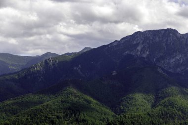 Çarpıcı bulutlu gökyüzünün altında, engebeli Tatra Dağları 'na yakın çekim yaparak heybetli ölçeklerini gösterirler..